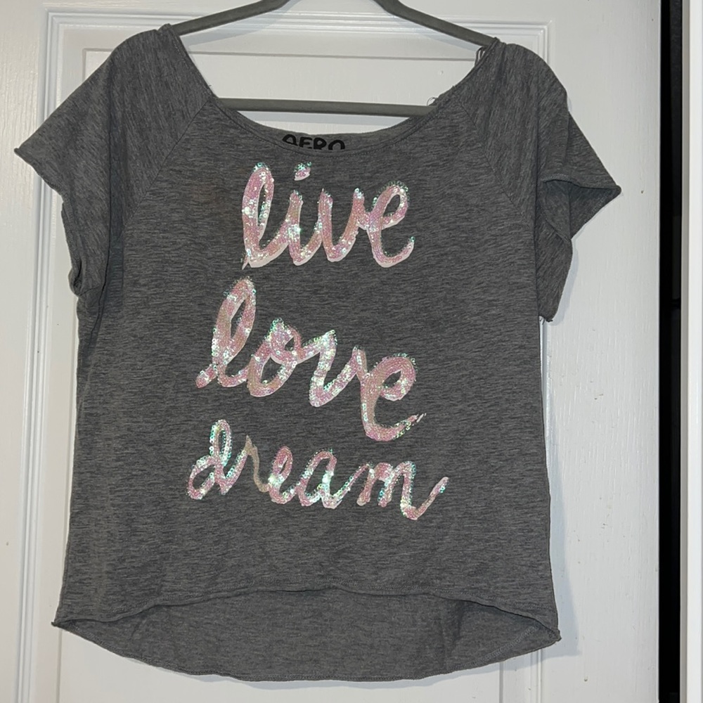 gray shirt with cursive sparkly letters spelling out “live, love, dream”